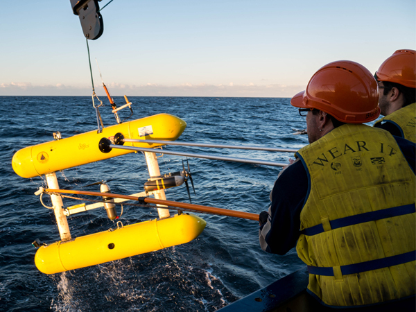 A survey instrumetn being pulled out of the water by two scientists