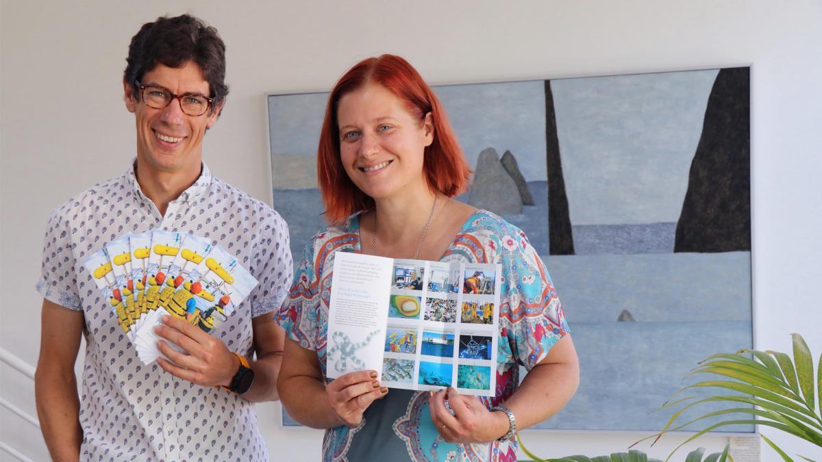 Scott Foster and Rachel Przeslawski hold flyers promoting the marine sampling field manuals